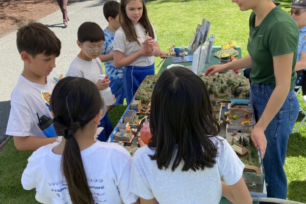 A group of children gather around a watershed model.